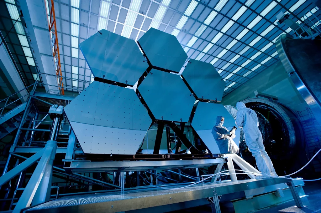 La imagen muestra a dos personas trabajando en lo que parece ser un telescopio o un dispositivo similar.