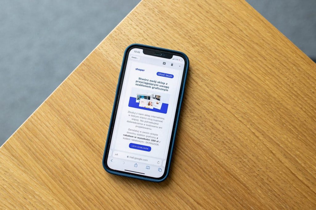 Smartphone mostrando una aplicación web progresiva PWA en el navegador móvil sobre superficie de madera