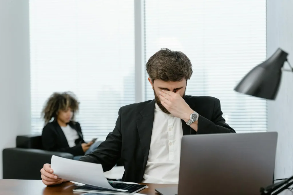 En la imagen aparece un dev cansado en la oficina, representando La carga mental en la industria tech: cómo sobrellevarla y evitar el burnout como developer