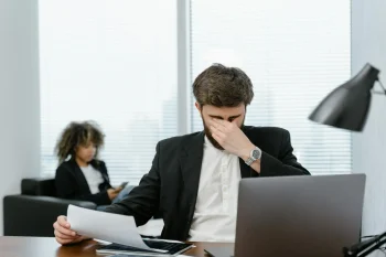 En la imagen aparece un dev cansado en la oficina, representando La carga mental en la industria tech: cómo sobrellevarla y evitar el burnout como developer