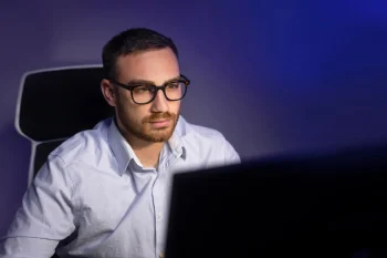 Joven consiguiendo trabajo IT sin experiencia frente a computadora con código en 2026