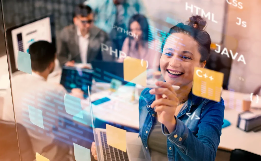 Profesional IT sonriente escribe en pizarra con lenguajes de programación como Python, Java y HTML