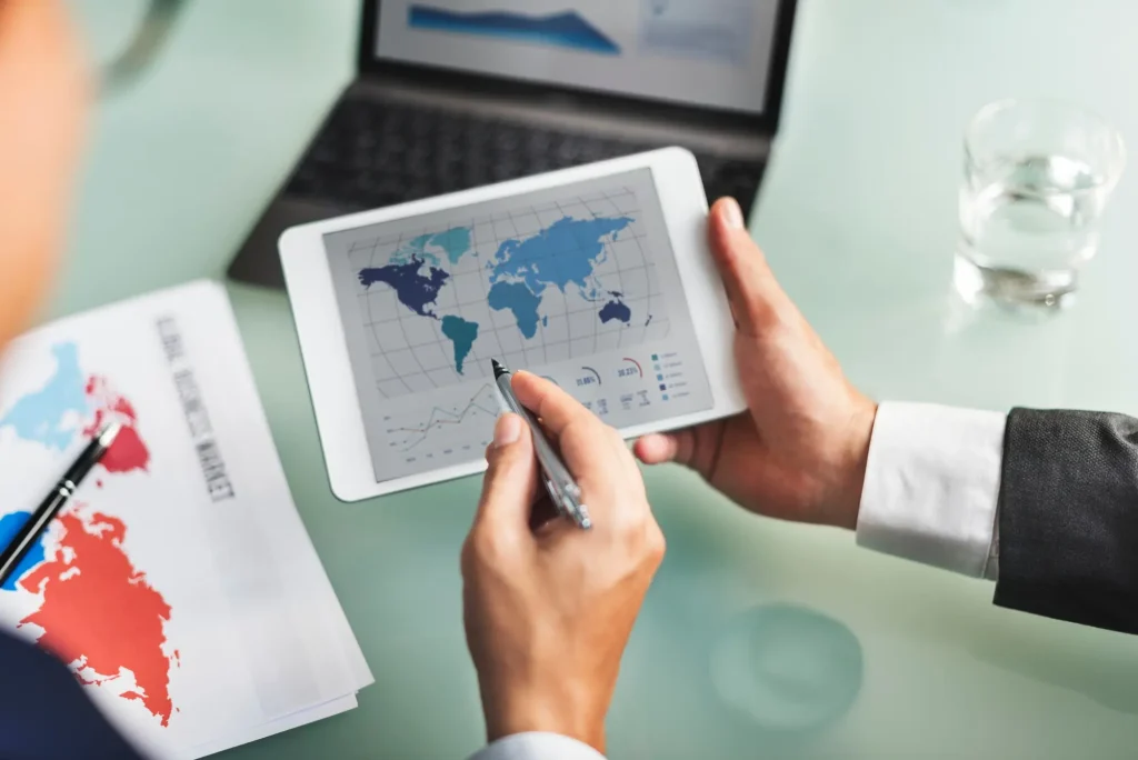 Ejecutivo señalando un mapa mundial y datos de mercado en una tableta digital, simbolizando el offshoring